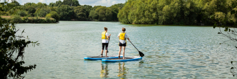 Two people standing on paddle boards on the lake