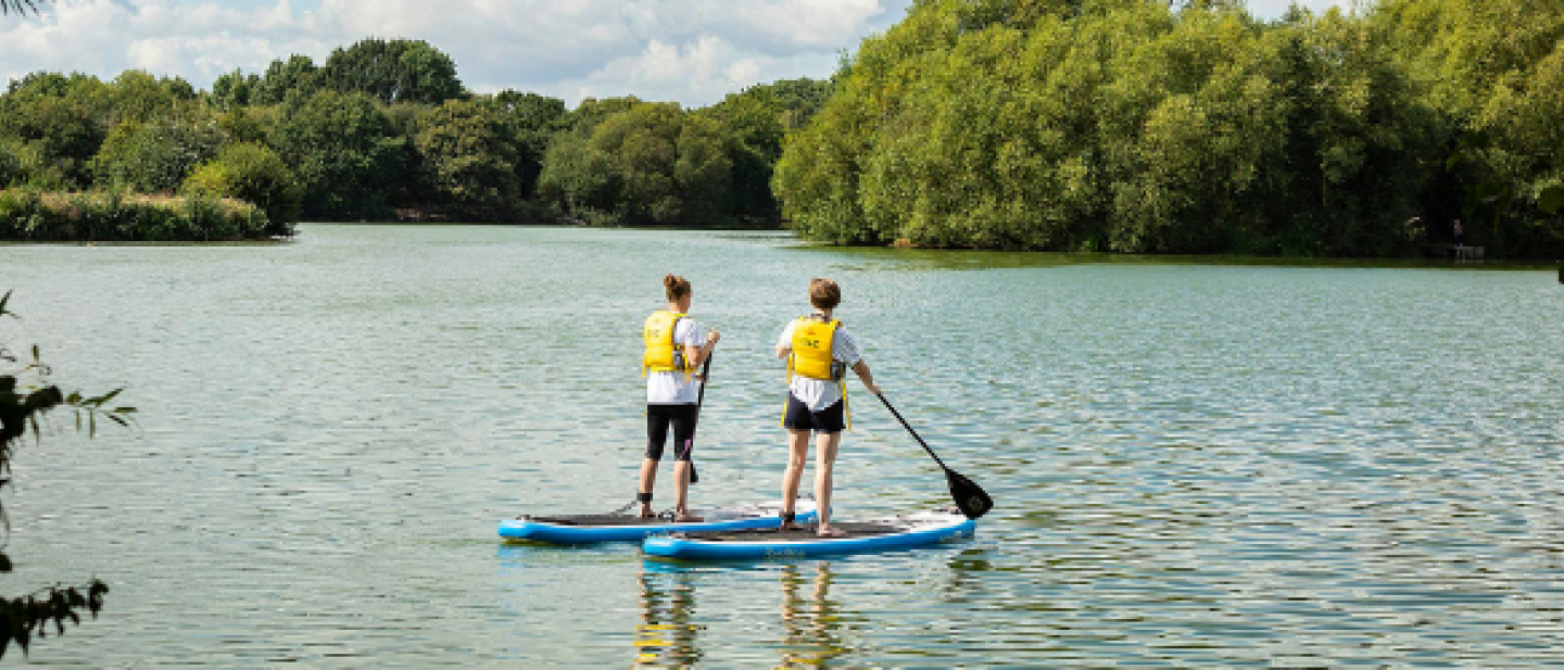 Paddle boarders standing on the lake being guided by an instructor