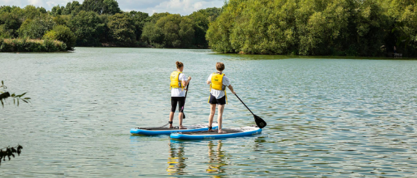 Two people standing on paddle boards on the lake